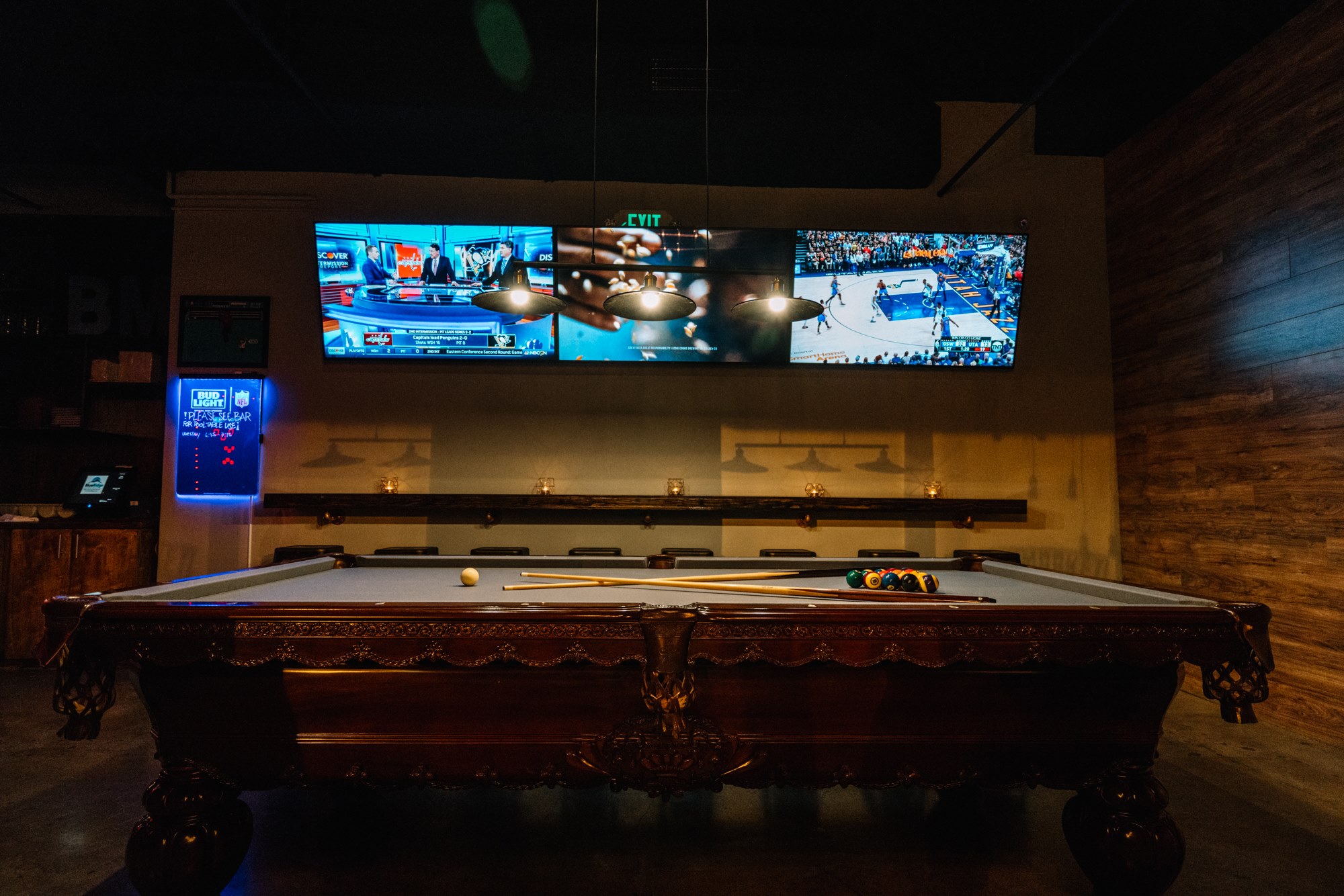 Carved pool table under a triple-screen video wall
