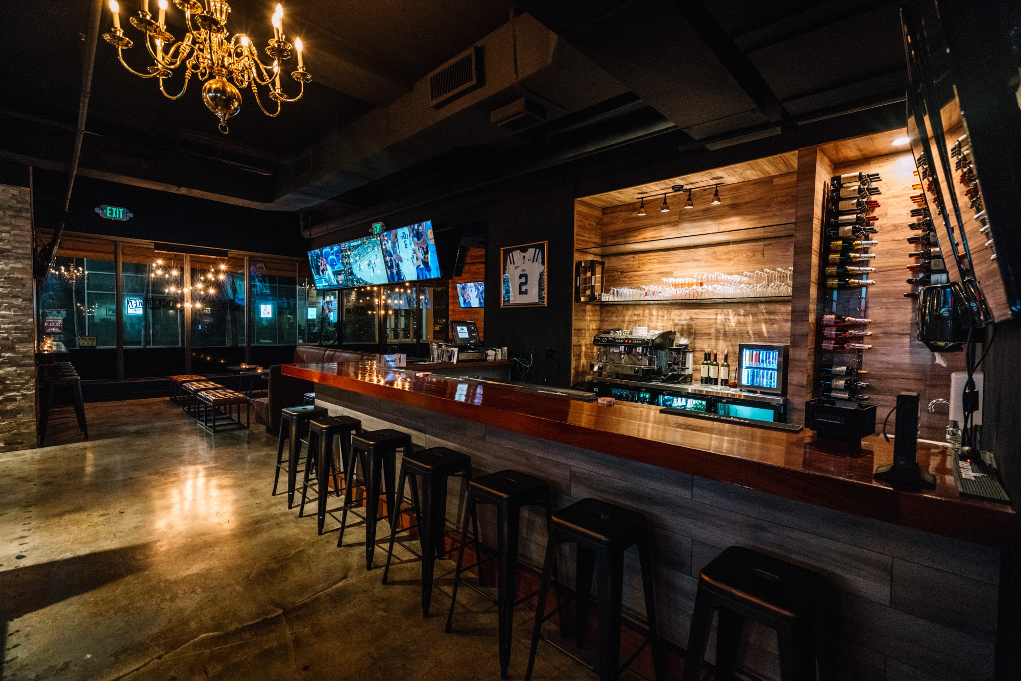 Main bar with brass chandelier, wood back-bar and wine wall