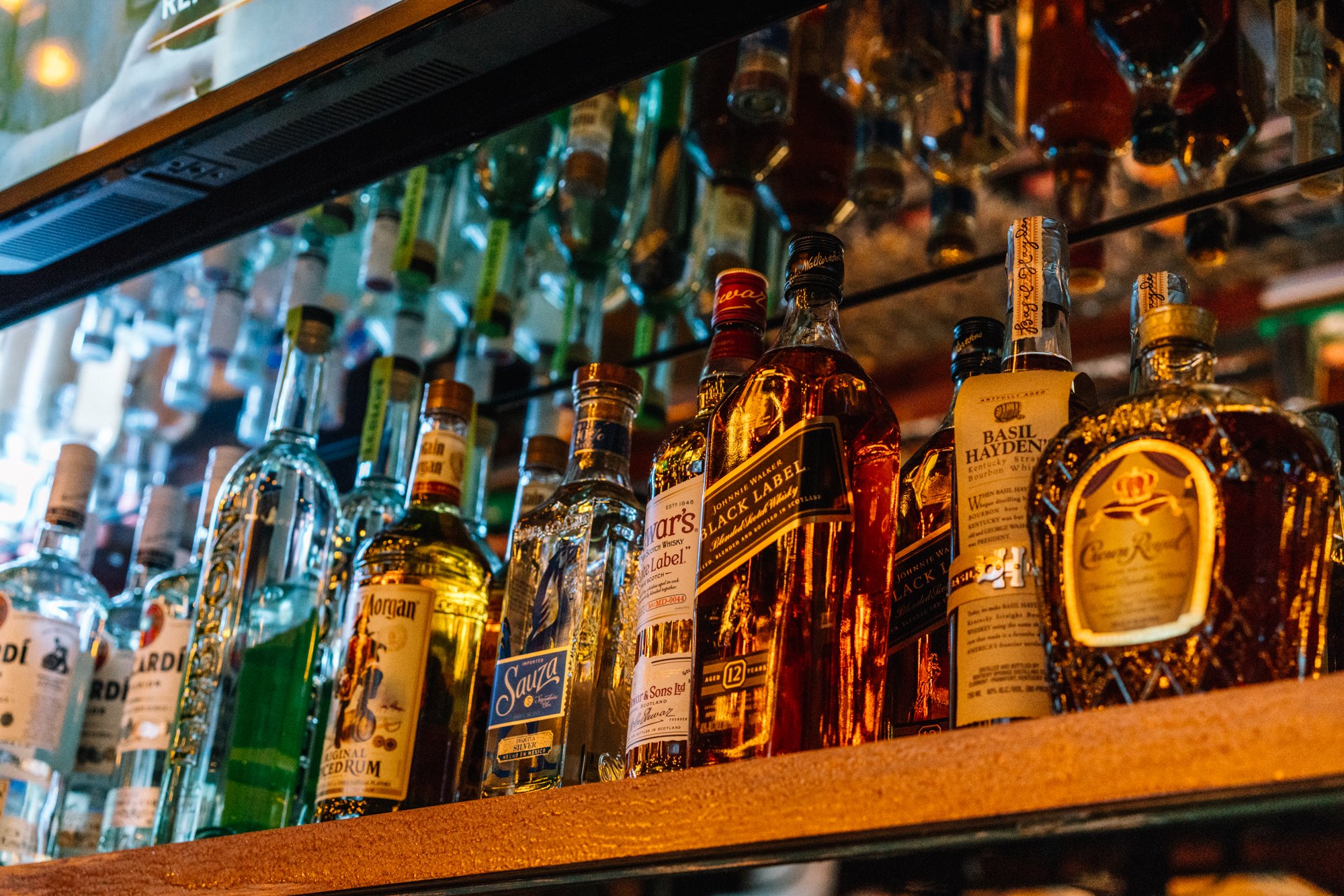 Top-shelf bottles glowing on the back-bar shelf