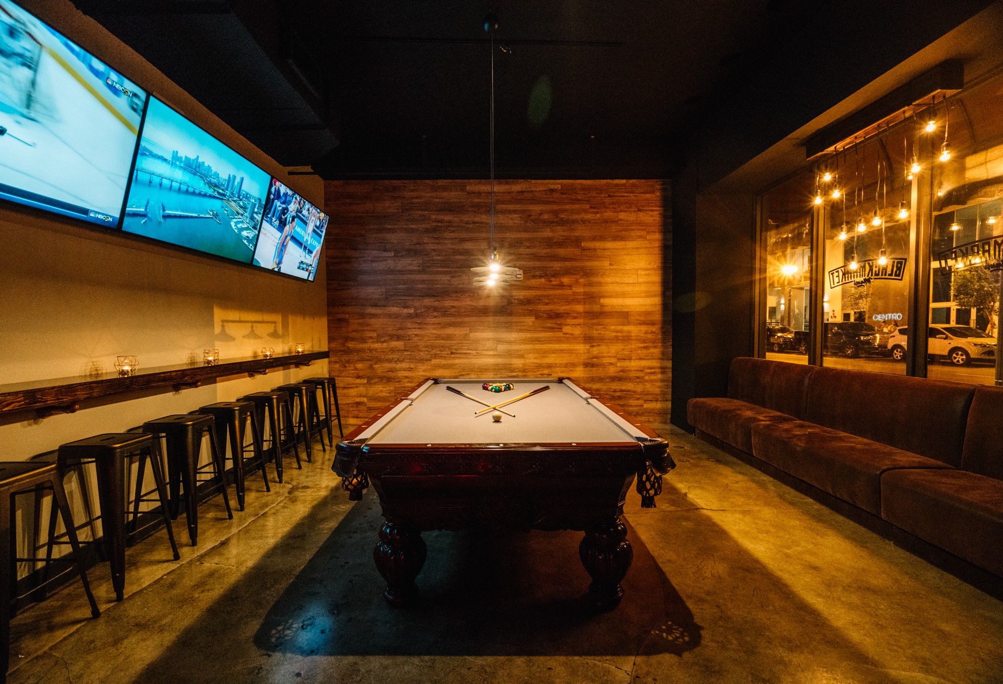Back pool room with bar stools and the reversed BLACKMARKET window sign