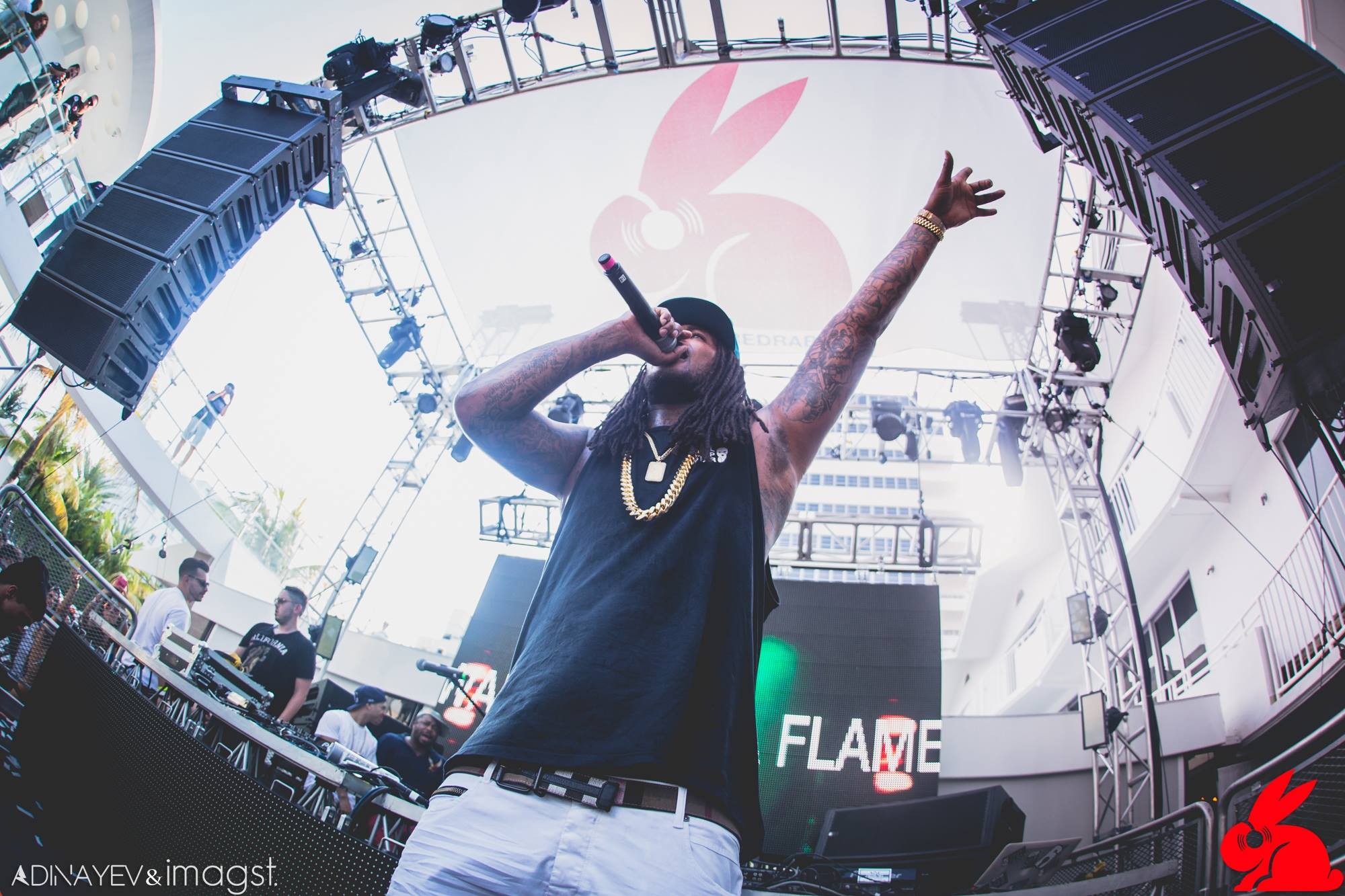 Headliner with arms raised on stage as flames fire in front of a giant LED screen