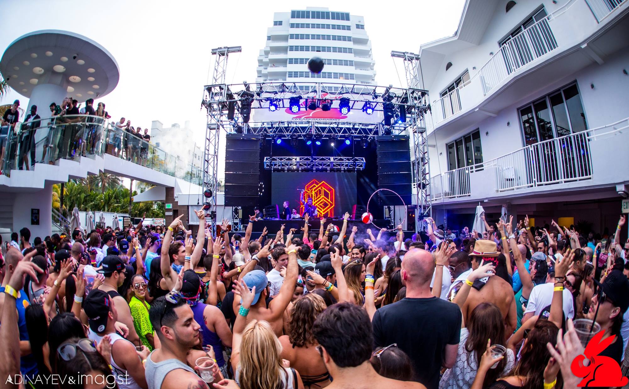 Daytime pool stage and crowd beneath the red Red Rabbit hexagon logo