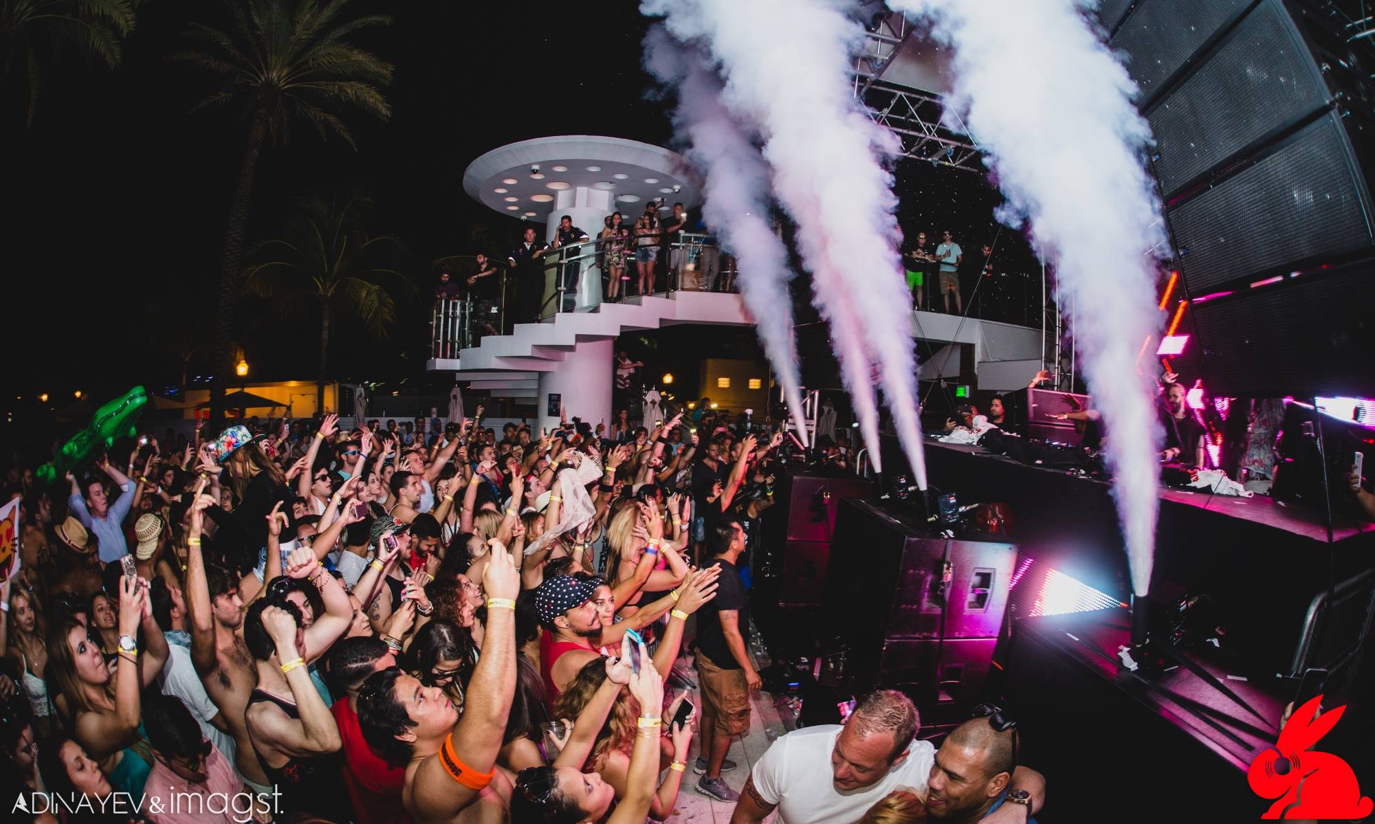 CO2 jets firing over a hands-up night crowd in pink stage light