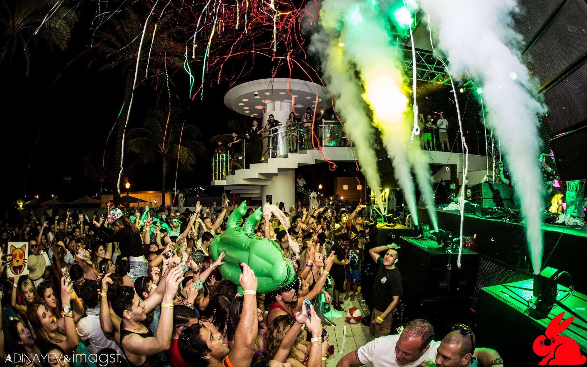 DJ playing with an inflatable T-rex at the booth in front of a giant LED screen
