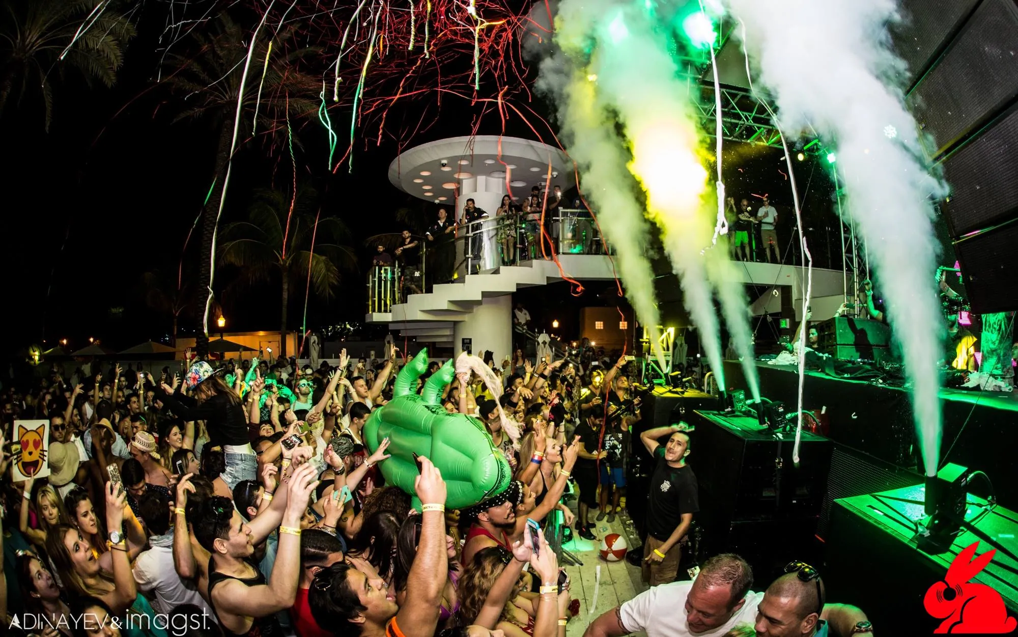 DJ playing with an inflatable T-rex at the booth in front of a giant LED screen
