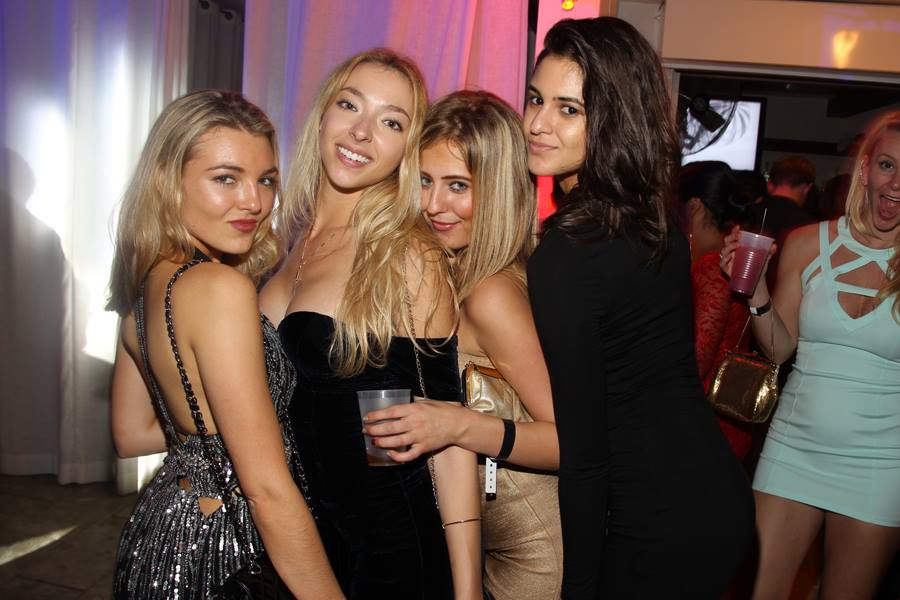 Four friends in cocktail dresses posing together on the dance floor