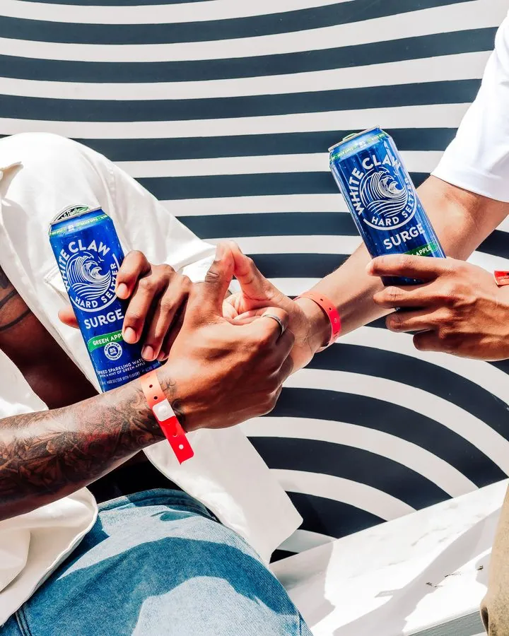 White Claw Surge cans in hand against the striped wall