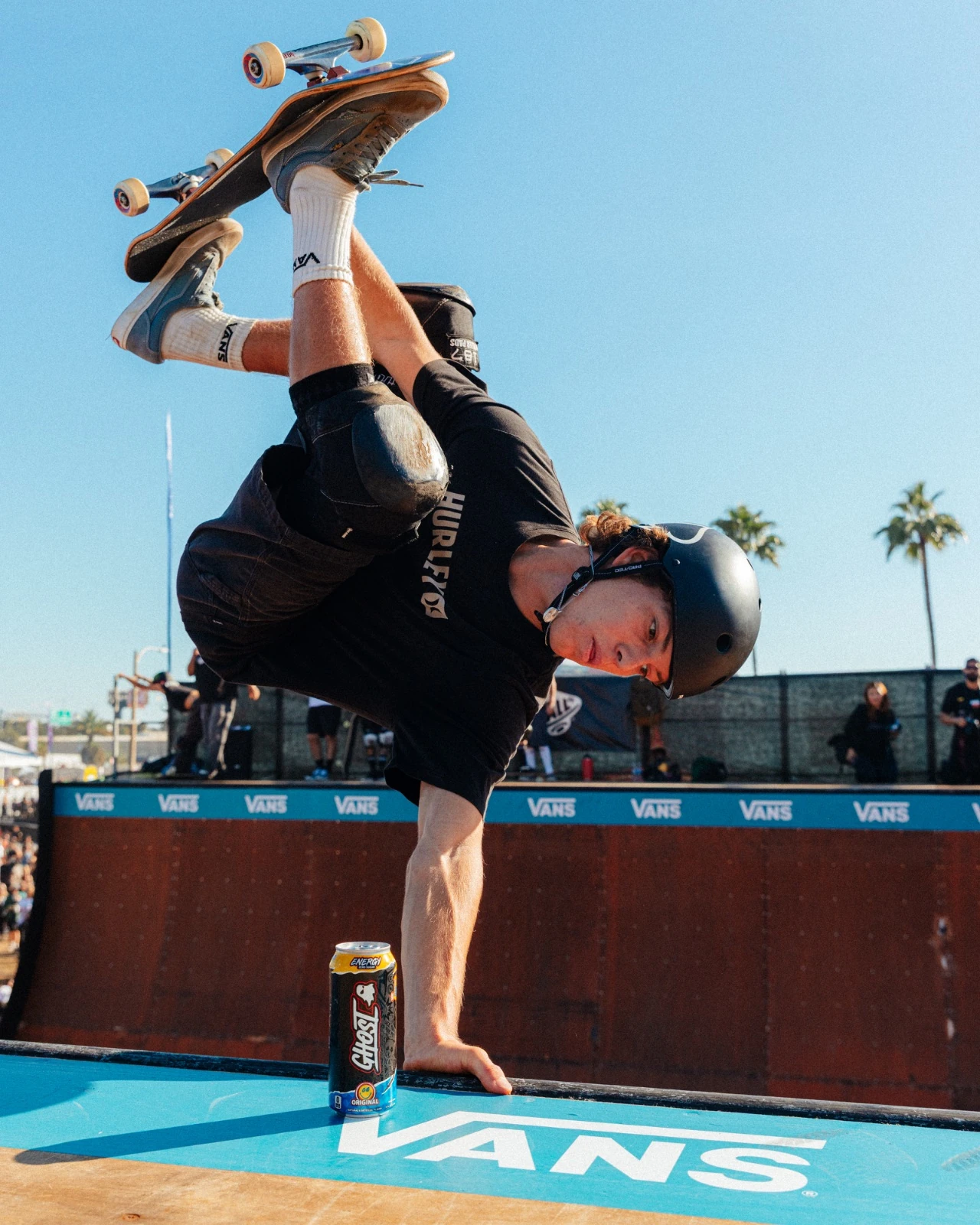 Skater holding a one-handed invert over the Vans ramp coping, GHOST can in foreground