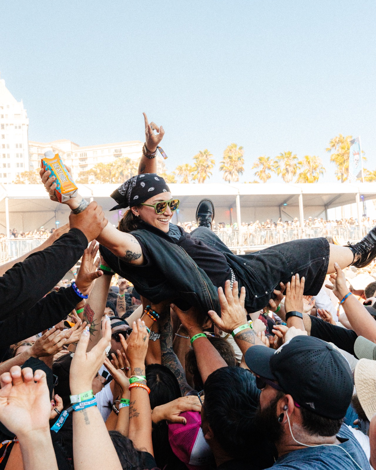 Crowd surfer carried over the pit holding a BeatBox carton, hands raised