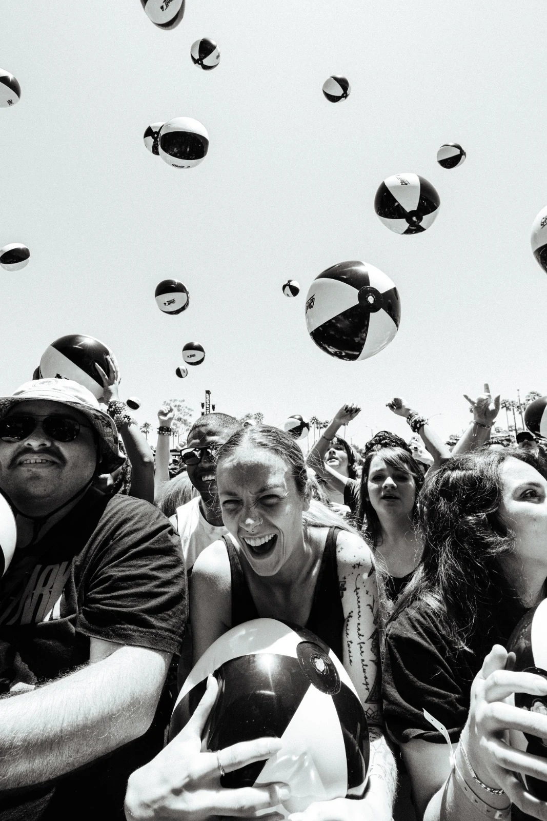 Black-and-white crowd shot with branded beach balls flying overhead