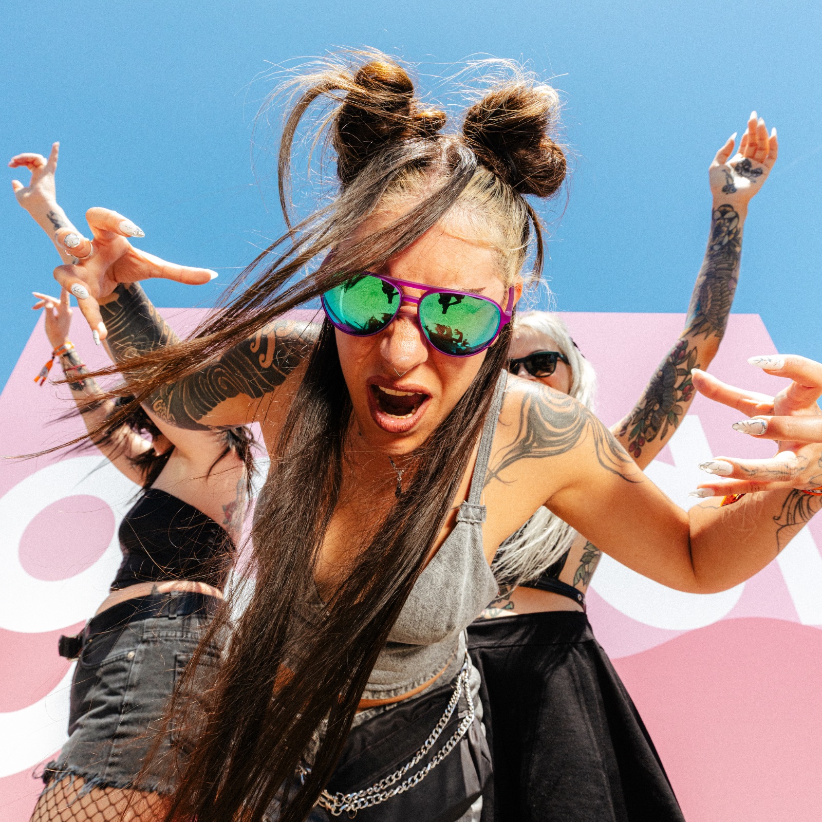 Two fans headbanging in goodr shades against a pink goodr backdrop