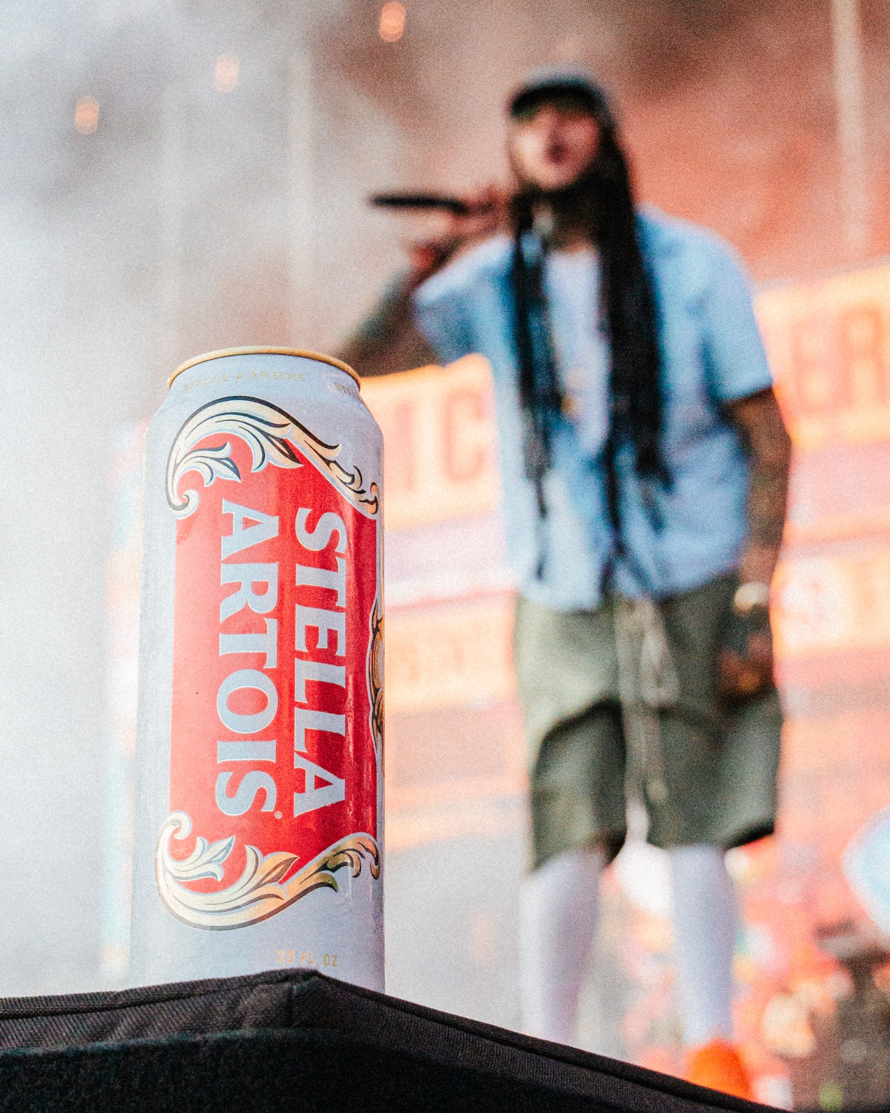 Stella Artois can on the stage edge with a performer silhouetted in haze behind