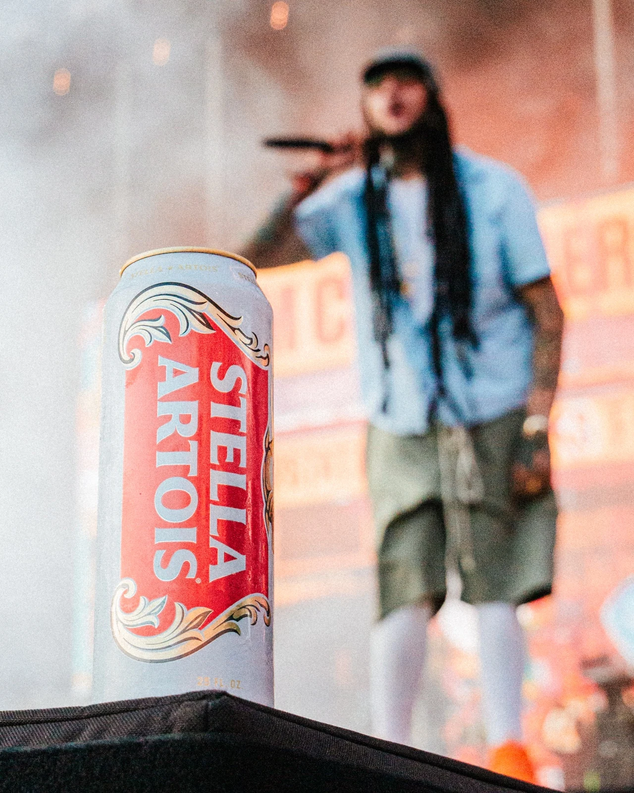 Stella Artois can on the stage edge with a performer silhouetted in haze behind